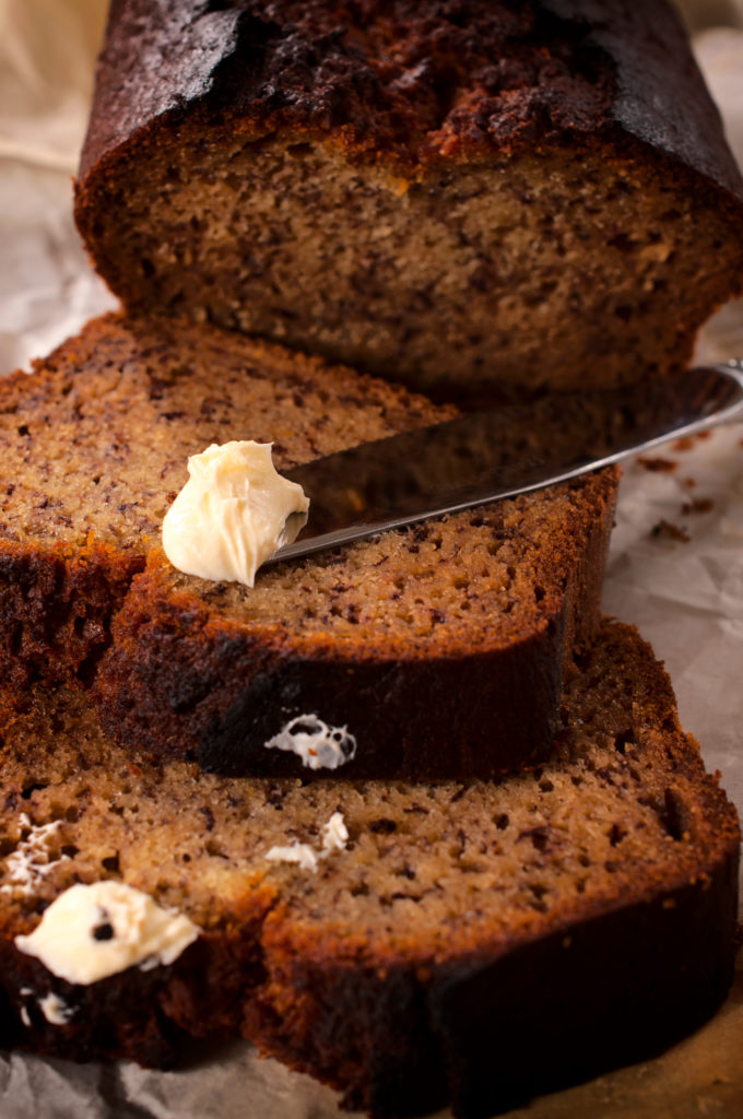 Selective focus on the knife with butter and bananas bread