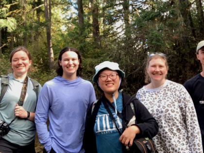 The four interns stand in a line with Director of Conservation Brittany Michalski in the forest.